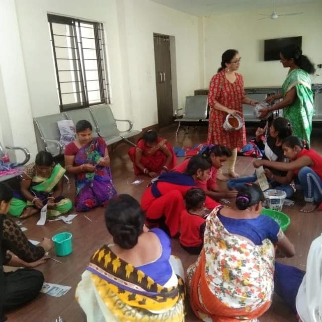 Trainees seated on the floor of a hall, shaping paper-clay pieces from strips of newspaper.