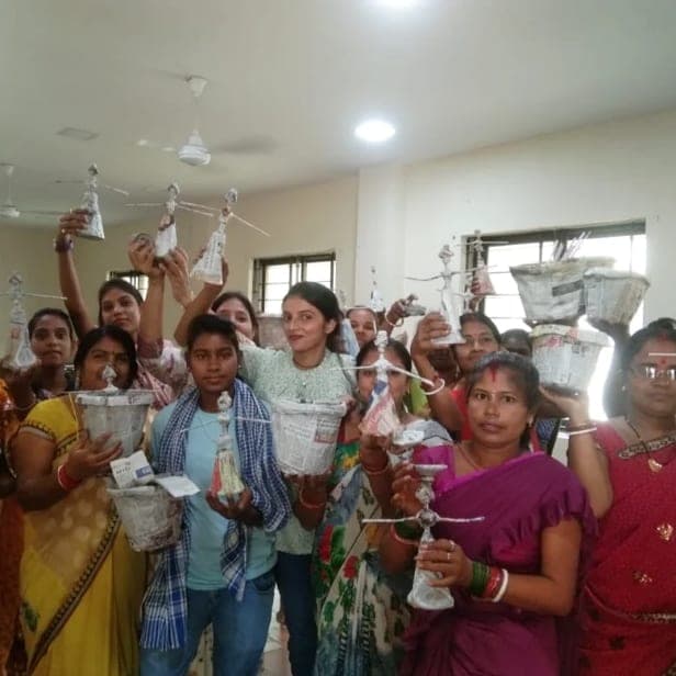 The group holding the unpainted paper-clay baskets and figures they made up above their heads.